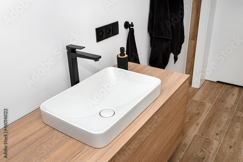 Fotografía A modern sink in the bathroom with a matte black tap, the floor is covered with ceramic tiles imitating wood