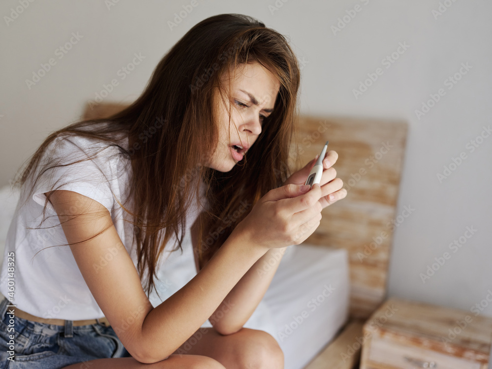 indignant woman sitting in a hotel and looking at a thermometer indignant woman sitting in a hotel and looking at a thermometer