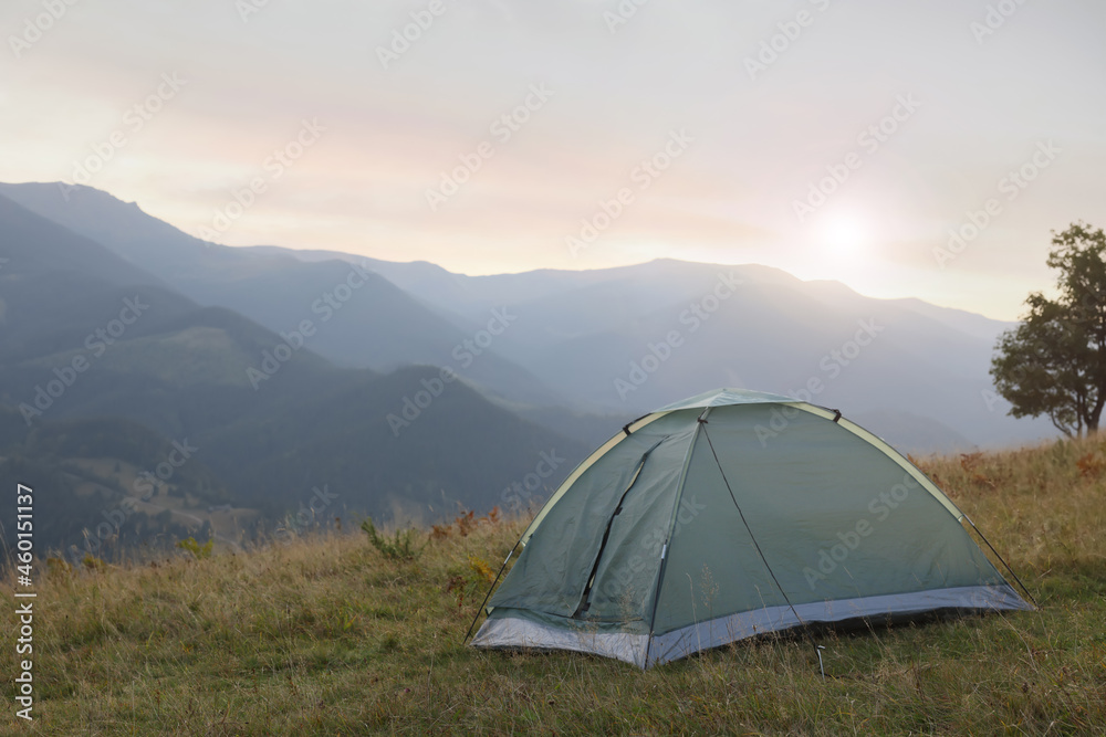 Grey camping tent in mountains at sunrise, space for text