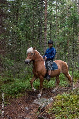 Man horseback riding in forest