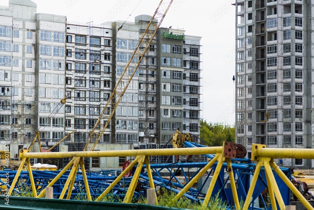 Large construction site including several cranes working on a building complex, with clear blue sky and the sun Large construction site including several cranes working on a building complex, with clear blue sky and the sun