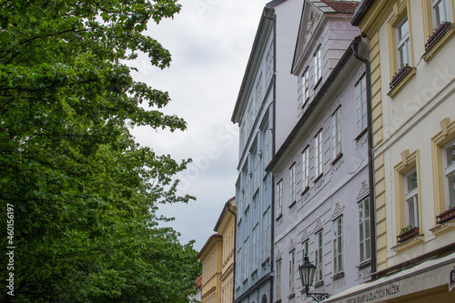 Facade of typical colorful czech houses with trees at the foreground in Prague, Czech Republic