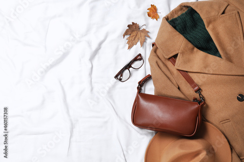 Flat lay composition with stylish hat and autumn clothes on white fabric, space for text