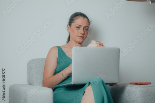 Mujer de negocios sentada en el sillón de su habitación haciendo una videollamada para una reunión de empresa de forma remota y online
