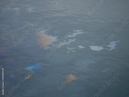 Dirty oily film on the surface of the turquoise sea on the beach. industrial dump waste water spill. Oil film pollution. Colorful oil film on water. industrial dump waste water spill. rainbow in sea