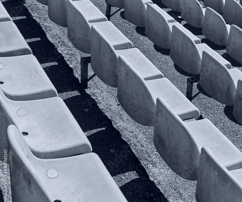 Rows of stadium grandstand seat. Rusty plastic white stadium seat.  Black and white photo.