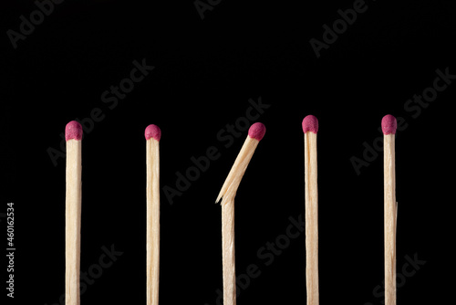 Row of matchsticks, all good, one broken in the middle. Close up shot of matches on black background, studio shooting.