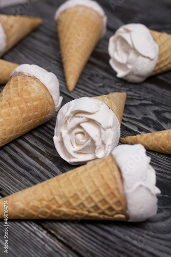 Homemade marshmallows are spread out on the table surface. Zephyr in a waffle cone. Made in the shape of a rose. Close-up shot.