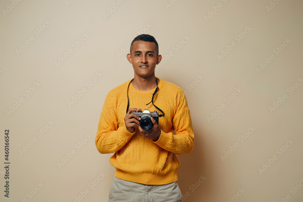 Young latinx man photographer holding with the hands an analog camera looking at camera. Young latinx man photographer holding with the hands an analog camera looking at camera.
