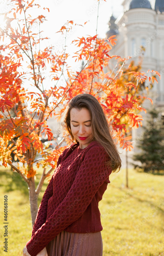 Beautiful woman in burgundy sweater walking in autumn park Beautiful woman in burgundy sweater walking in autumn park