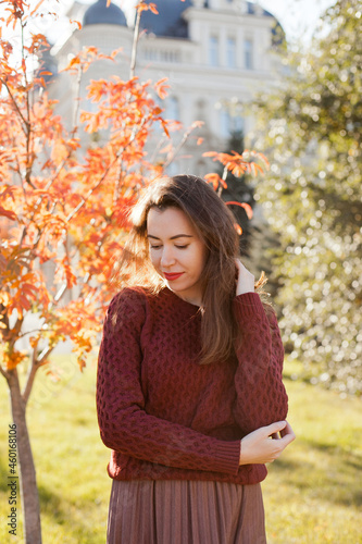 Beautiful woman in burgundy sweater walking in autumn park