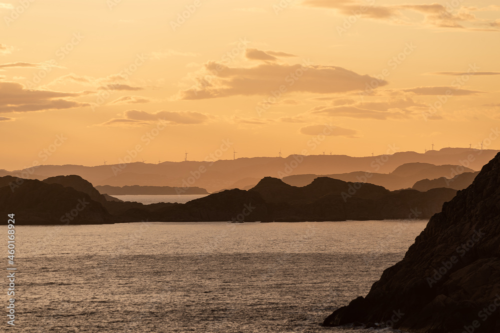 Golden sunset over an archipelago with wind turbines in the horizon.