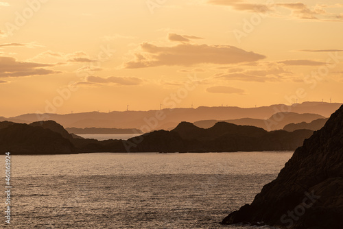 Golden sunset over an archipelago with wind turbines in the horizon. © Trygve