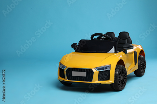 Child's electric toy car on light blue background. Space for text photo