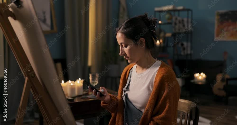 Beginning artist draws a new painting inspired by another masterpiece, girl plays sketch,takes phone, zooms in on photo, shrugs shoulders, holds phone high to glance at smartphone