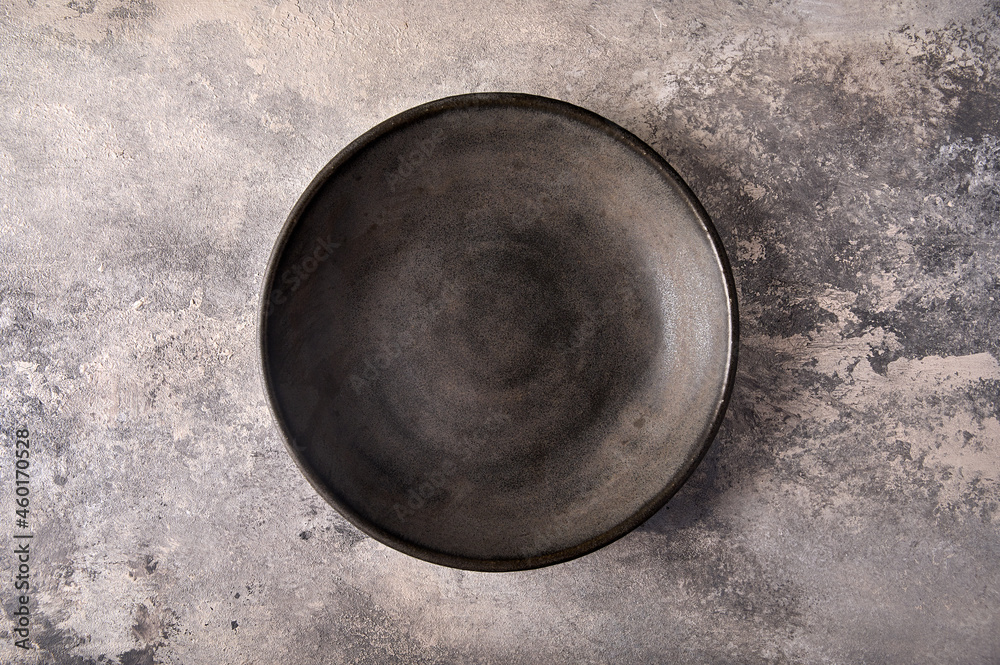 Empty dark deep plate on gray textured background as concrete. Top view, copy space Empty dark deep plate on gray textured background as concrete. Top view, copy space