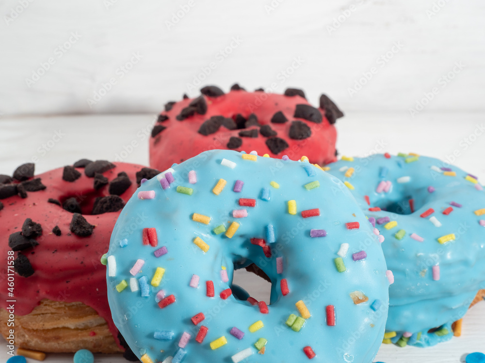 Red and blue cronuts on a white wooden background.
