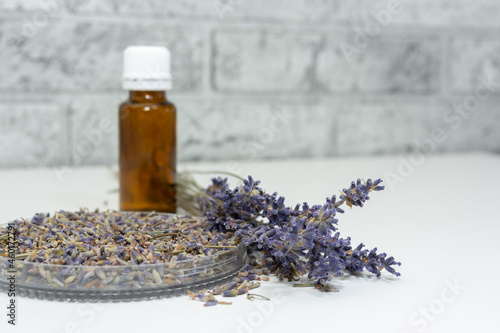 Lavender seeds on a white table near a bouquet of flowers and a bottle