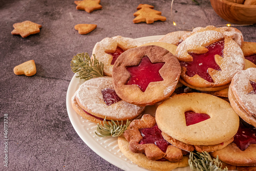Delicious homemade Christmas cookies with jam, copy space. Traditional Linzer cookies on a dark table, copy space