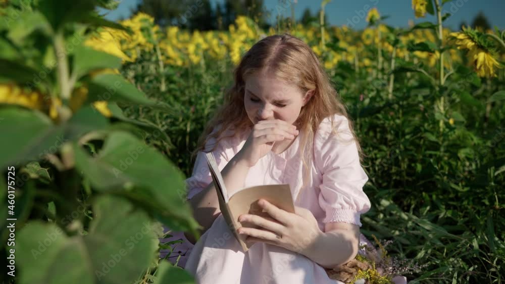 a young pretty blonde caucasian girl with curly hair in a light dress in a sunflower field on a sunny day smiles, reads a book, looks around, waits a young pretty blonde caucasian girl with curly hair in a light dress in a sunflower field on a sunny day smiles, reads a book, looks around, waits