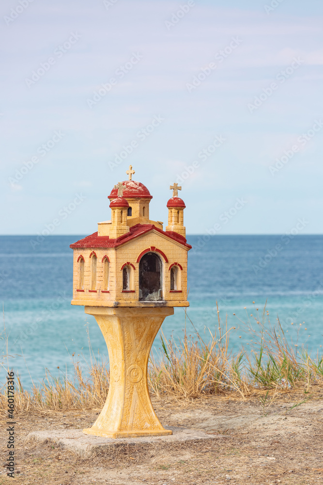 Traditional and memorial small chapel or church in Greece with sea in background