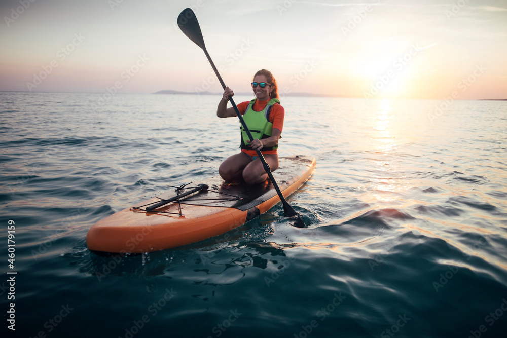 Woman paddleboarding on a sunset sea