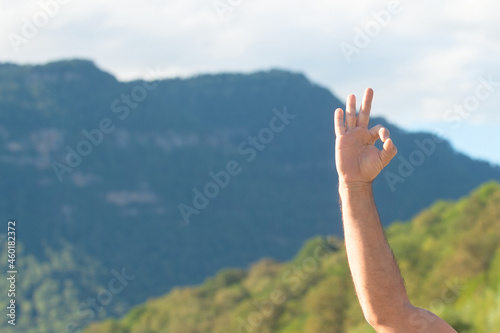 A man shows his hand an OK sign, on the background of nature in the mountains. Great trip.