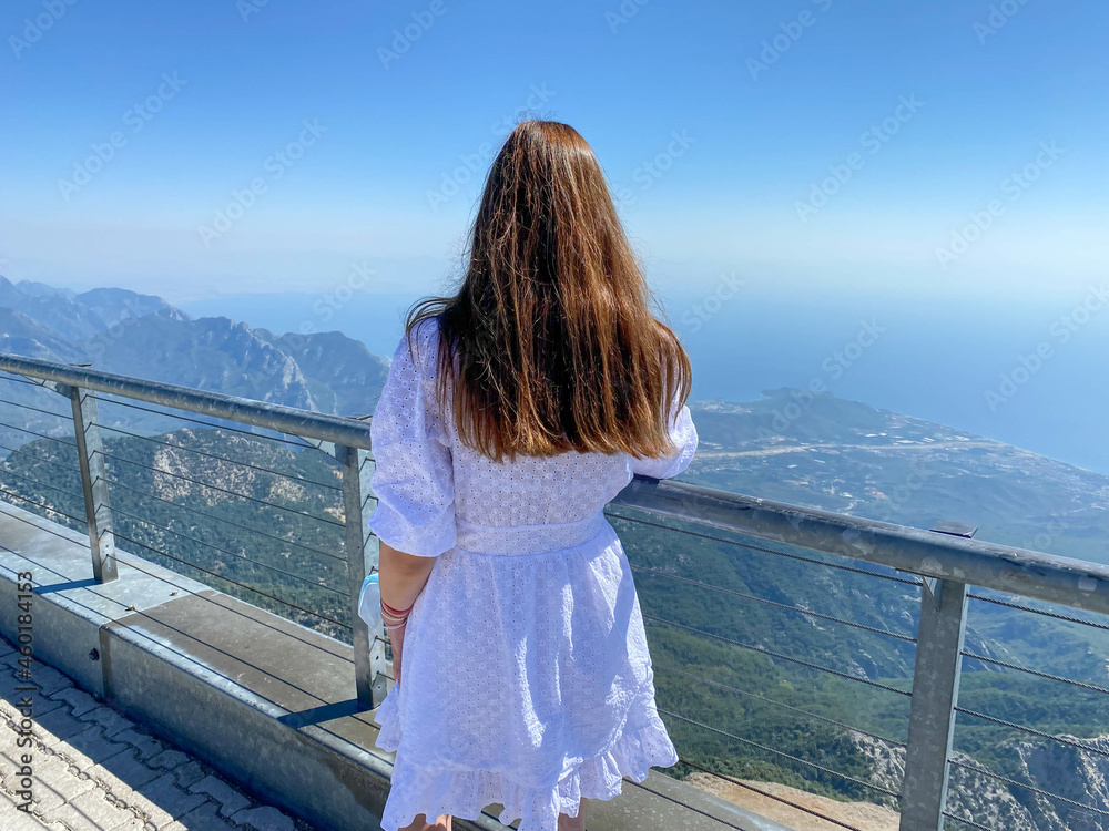 backpack travel girl stay back to camera on hotel balcony observation deck place with picturesque view on tropic Mediterranean summer landscape sea bay surrounded by steep rocks and mountains