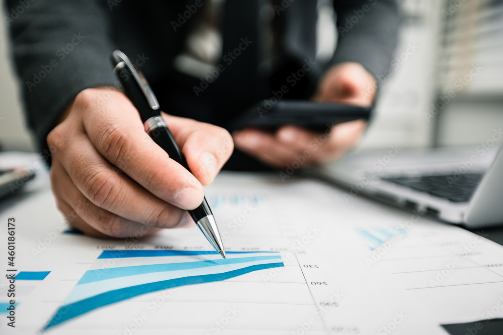 Close up of businessmen using smartphone and laptop computer working business report analytic at home, accounting document, marketing and financial business concept.