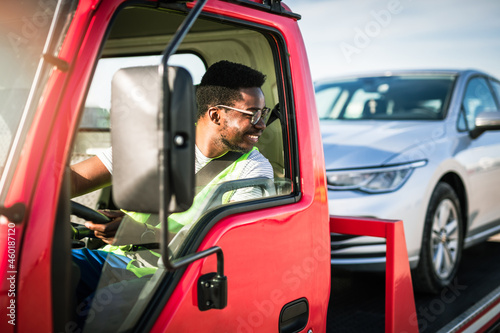 Handsome young African American man working in towing service on the road. Roadside assistance concept.