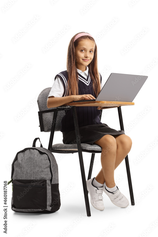 Schoolgirl sitting in a classroom chair and using a laptop computer Schoolgirl sitting in a classroom chair and using a laptop computer