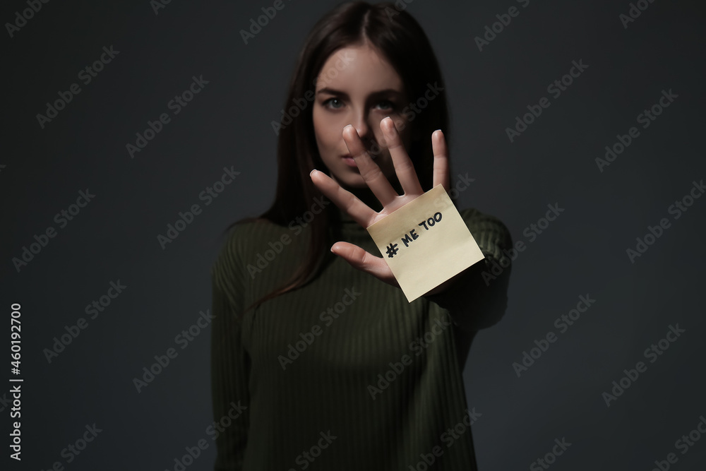 Note paper with hashtag MeToo on hand of young woman against dark background - obrazy, fototapety, plakaty 