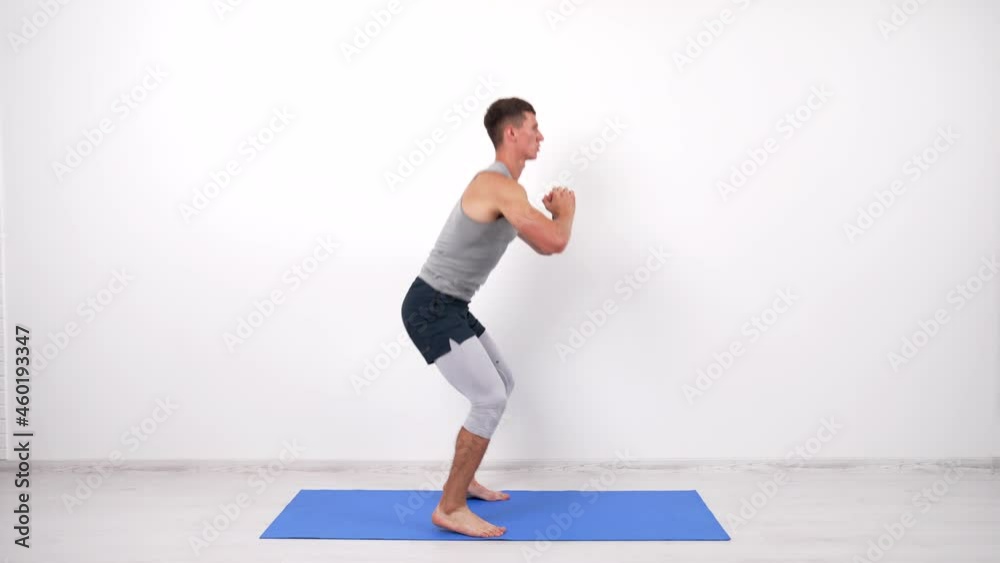 athletic man doing squats and jumping on fitness mat, squatting athletic man doing squats and jumping on fitness mat, squatting