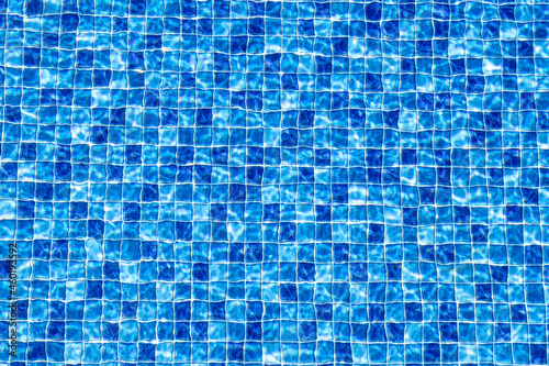 Fundo de uma textura de piscina com a sensação da água em movimento. Estampa em mosaico de pequenos quadrados em diferentes tons de cor azul. Foto com visão do topo.
