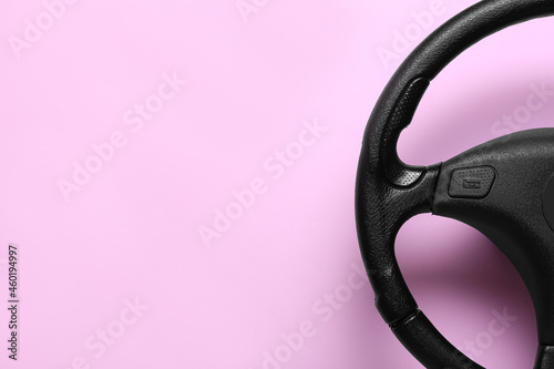 Black modern steering wheel on color background, closeup