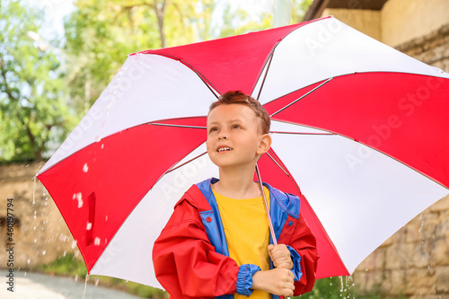 Cute little boy with umbrella outdoors on rainy day