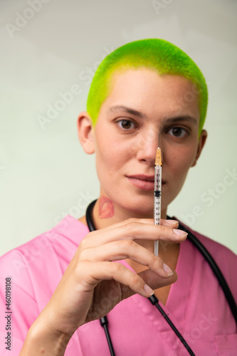 Health care worker in pink scrubs prepares a syringe for vaccination.