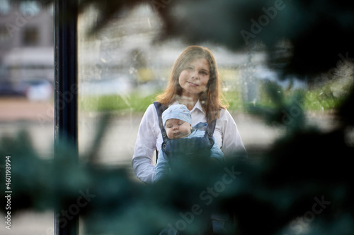 Mother with sleeping infant in baby sling outdoors.