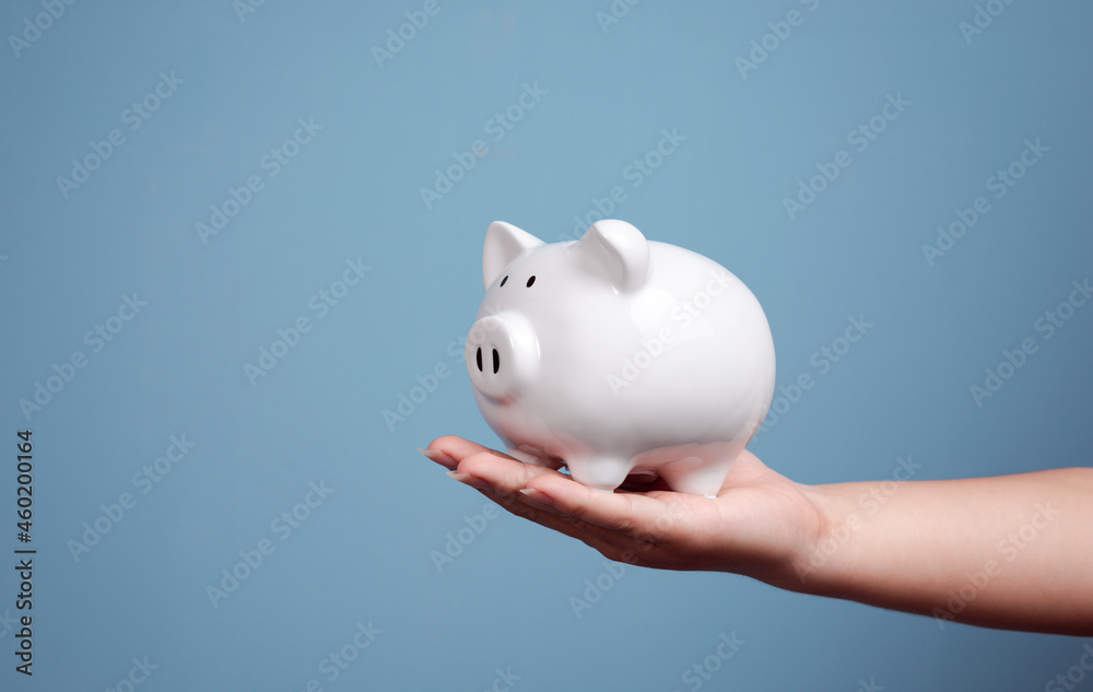 Man hand holding piggy bank for saving money on blue background. Man hand holding piggy bank for saving money on blue background.
