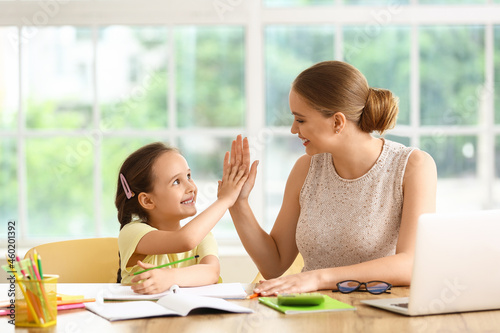 Little girl and her mother giving each other high-five at home