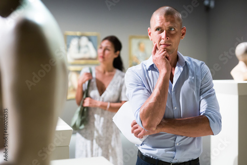 Thoughtful adult man watching statues in museum hall