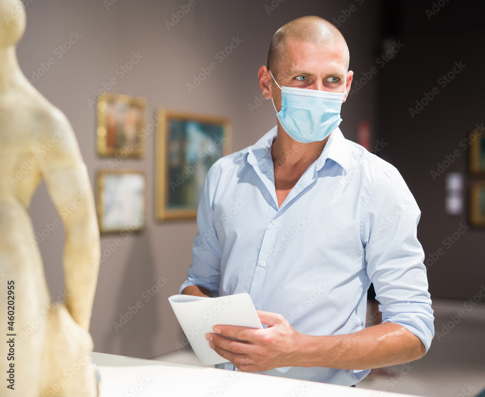 European man with mask admiring art work in museum
