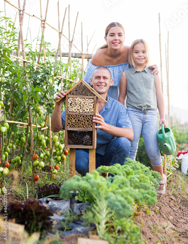 Family spending time together beside insect hotel in kitchen garden
