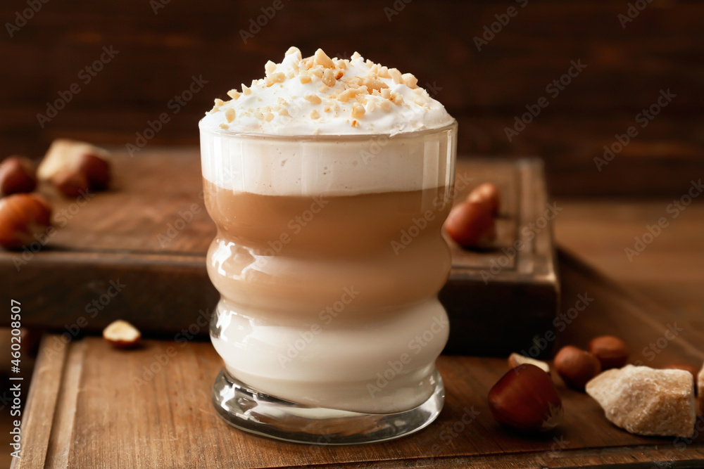 Glass of tasty latte with nuts on wooden background Glass of tasty latte with nuts on wooden background