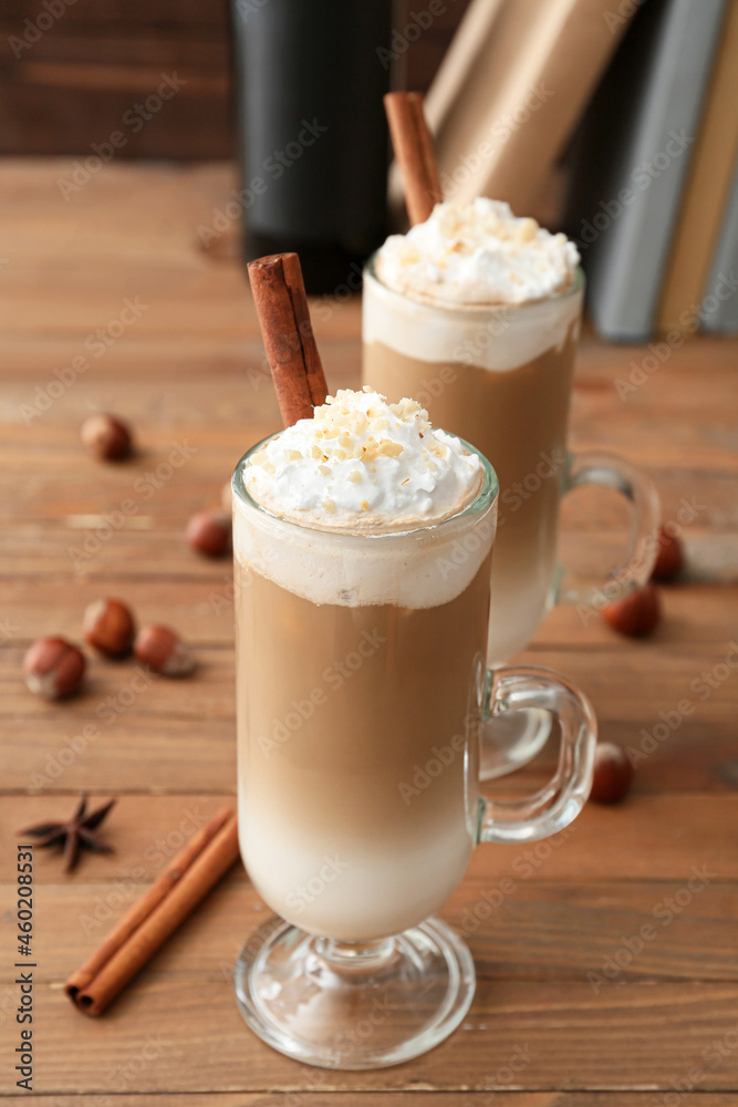 Glass cups of tasty latte with nuts on wooden background Glass cups of tasty latte with nuts on wooden background