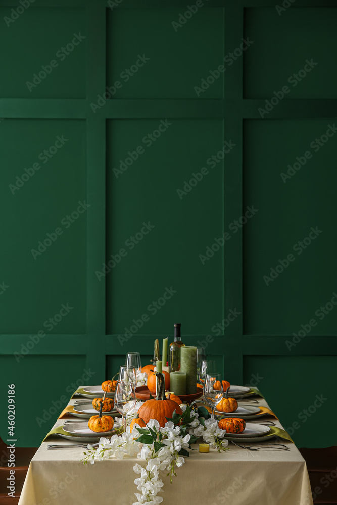 Autumn table setting with fresh pumpkins and flowers near green wall ...