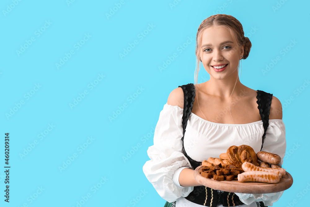 Beautiful woman in traditional German costume and with snacks on color background Beautiful woman in traditional German costume and with snacks on color background