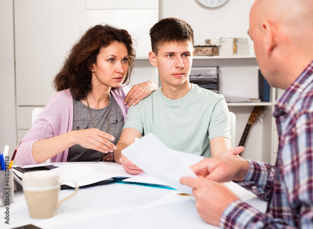 Obraz premium Young woman with her husband and teen son calculating domestic budget at table ..
