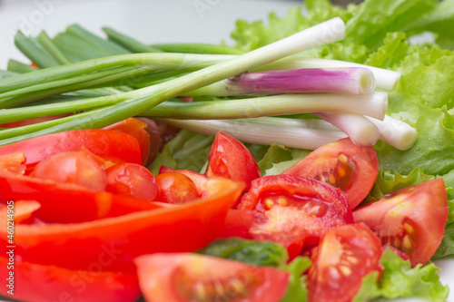 chopped green onions, tomatoes and lettuce lie on a white plate