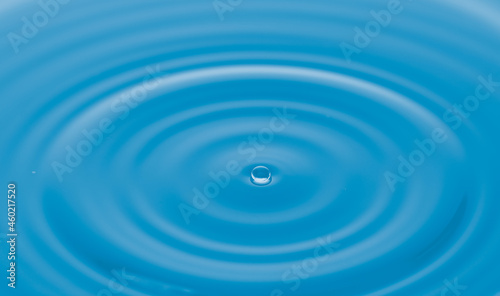 Water droplets on water surface with blue light effects background.